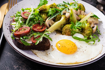 Breakfast with fried egg, broccoli, mushrooms and tomato sandwich. Healthy balanced food.