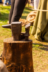 iron anvil on a wooden stump for forging metal. vertical photo on a sunny day at a rural fair