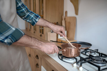 Man in a checkered shirt and apron putting the pan on the oven