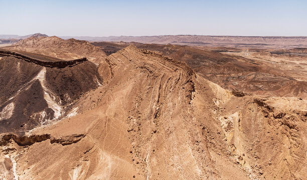aerial closeup of the makhtesh ramon crater in israel showing a chert and flint covered chalk hill on the left next to an ancient limestone formation