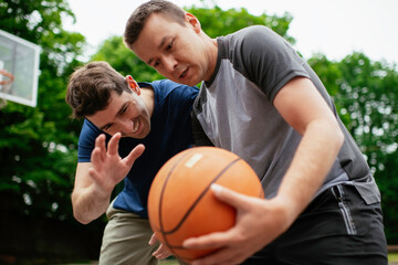 Two young men playing basketball in the park. Friends having a friendly match outdoors	
