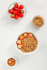 Homemade granola in a bowl with fresh strawberries, nuts and yogurt. Healthy and delicious Breakfast. The concept of summer food. Top view, selective focus.