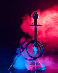 hookah shisha with glass flask and metal bowl with colored smoke on a black background