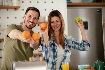 Young couple making breakfast at home. Loving couple preparing juice.	
