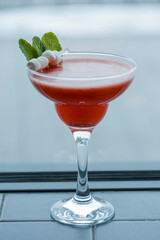 Cold summer alcohol cocktail with ice and fruit in a tall glass on light blurred restaurant or cafe background.