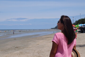 Asian women wearing pink shirts are stand with joy and freshness. On beach on summer holiday, Summer concept. Happy summer