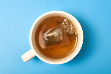 Tea bag in a white cup on a blue background. Making delicious herbal tea.