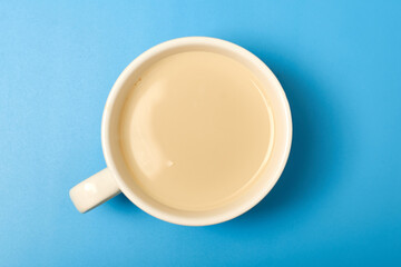 Tea with milk in a white big cup on a blue background.