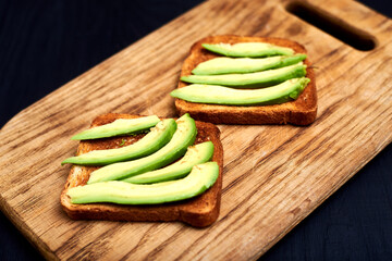 Toast with sliced avocado on a wooden background.