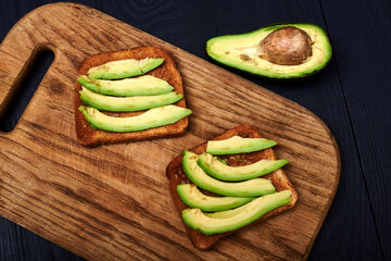 Toast with sliced avocado on a wooden background.