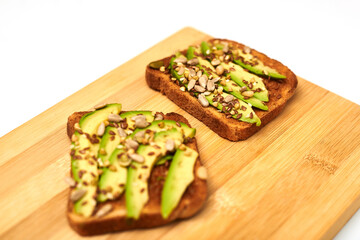 Toast with sliced avocado, mixture of seeds on a wooden background. Healthy snack tomorrow. The concept of proper nutrition, diet.