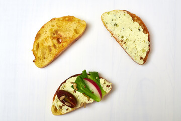 Ciabatta with cream cheese and vegetables on a white plate.