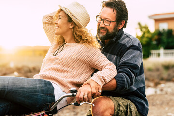 Happy adult people cheerful couple enjoy the outdoor leisure activity riding a bike together man...