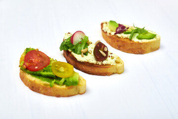 Ciabatta with cream cheese, avocado, various vegetables. Vegetarian sandwiches on a white background.