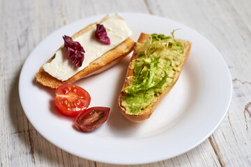 Toasted baguette with avocado, tomato and cheese. on a light wooden background.