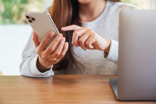 Jun 16th 2020 : A Woman Holding And Using Iphone 11 Pro Max Smart Phone With Apple MacBook Pro Laptop Computer On Wooden Table , Chiang Mai Thailand