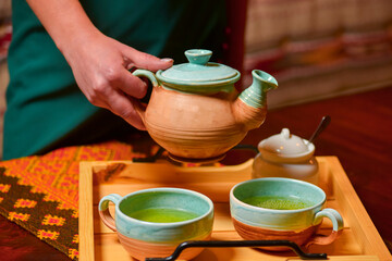 Composition with tea set. Traditional Ukrainian ceramic tea set. Tea-time. Woman pouring tea into a cup.