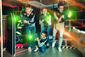 Modern young people with laser pistols playing laser tag on dark