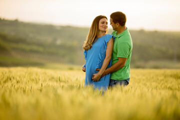 Young husband and his pregnant wife in the summer field