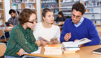 Teacher working with female students in library
