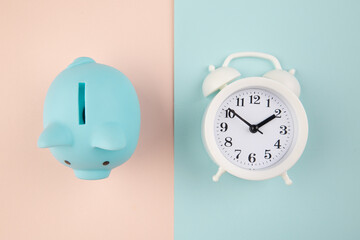 Time to invest. White clock and blue piggy bank on pink blue pastel background.