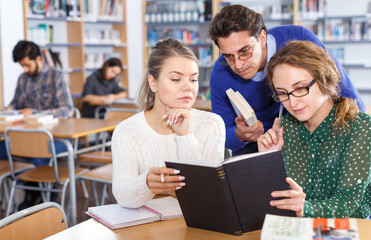 Fototapeta premium Teacher working with female students in library
