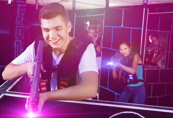 Portrait of excited guy with laser pistol playing laser tag in a
