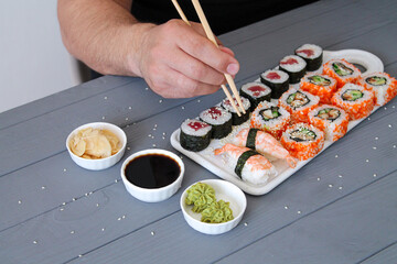 Man holding chopsticks and eating sushi set in a restaurant