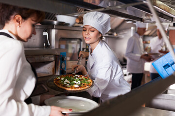Fototapeta na wymiar Female chef giving cooked pizza to waitress