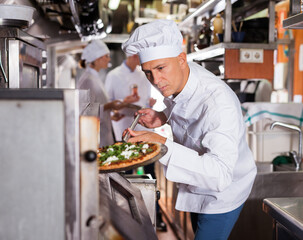 Confident chef getting pizza out of oven