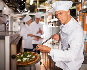 Chef with shovel with cooked pizza