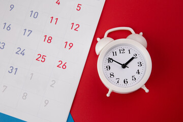 White alarm clock and calendar on colorful background.