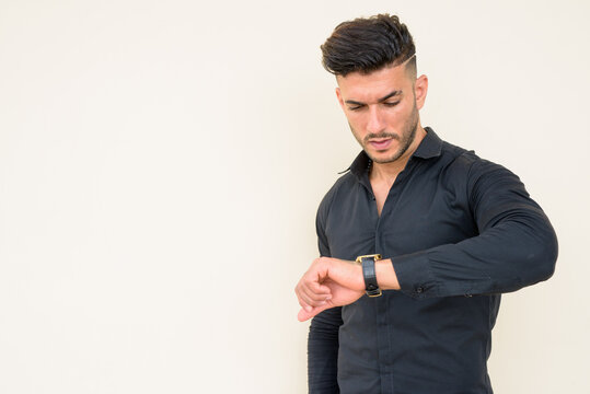 Young handsome bearded Persian businessman checking the time