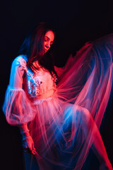 portrait of a sad girl in a dress dancing alone on a dark background