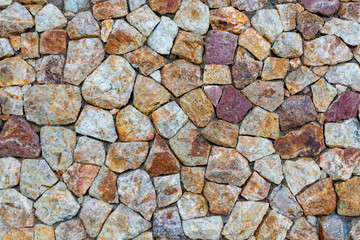 colored unprocessed rocky stones of natural origin, a wall of stones in concrete, background for walls and wallpapers