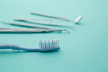 Dentist tools,mirror, spatula, tweezers and toothbrush on a blue background.