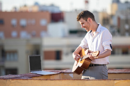 Joven cantante actuando por streaming en redes sociales en la azotea de un edificio al atardecer
