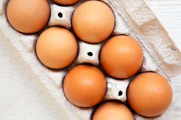 Raw Brown Eggs in a paper box, overhead view. Flat lay, top view, from above. Close-up.