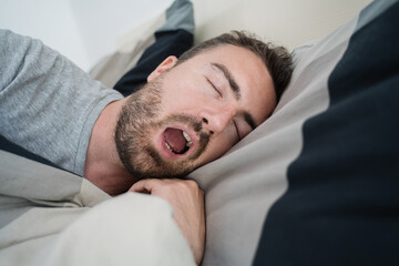 Man snoring loudly in his bed during night time