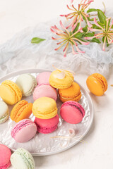 Colorful french macaroon cakes. Macaroons with jasmine flowers on white table background. Selective focus