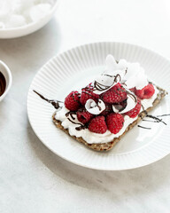 Snack with crispbread,cream cheese and fresh raspberries on white marble background. Healthy food concept.