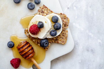 Snack with crispbread, goat cheese and fresh fruits on white marble background. Healthy food concept