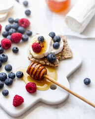 Snack with crispbread, goat cheese and fresh fruits on white marble background. Healthy food concept