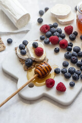 Snack with crispbread, goat cheese and fresh fruits on white marble background. Healthy food concept