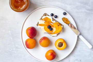Healthy breakfast toasts with ricotta cheese, apricots and Camembert on white marbke background