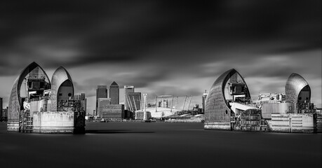 The Thames Barrier and Canary Wharf in the background. Black and white artcistic photograph of London