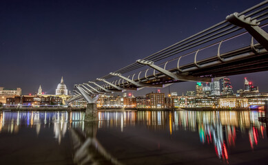 Fototapeta na wymiar Millennium Bridge at Night in london looking over the river Thames towards st pauls Cathedral with reflections of the city lights. 