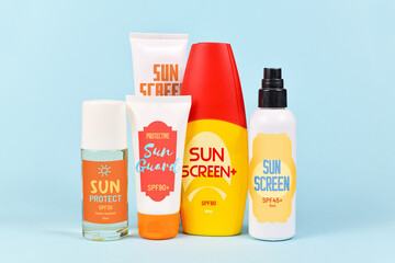 Different protective sun screen bottles and tubes with made up labels  on blue background