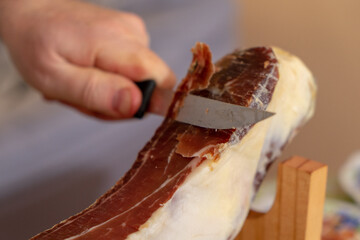 Man cuts mini ham with a special knife.