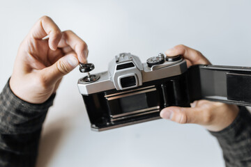 Male hand reloading film retro camera on a white table. Horizontal